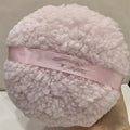 Large oval white plush powder puff for makeup on a plain background.