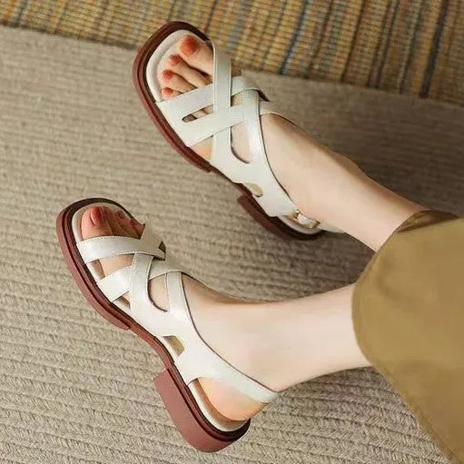 Women's glossy patent leather sandals with a square toe and flat low heel in black.