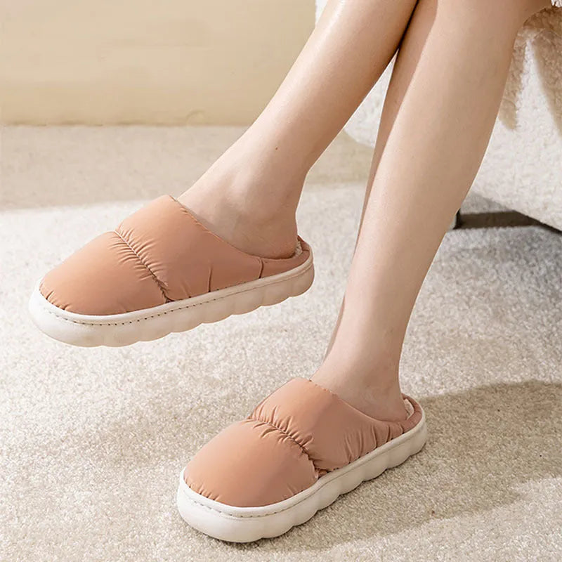 Blue down cotton indoor slippers with thick rubber sole and plush lining on a wooden floor.