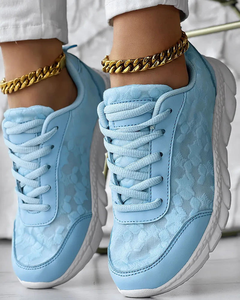 Women's white canvas running shoe with flat heel and soft sole on a light background.