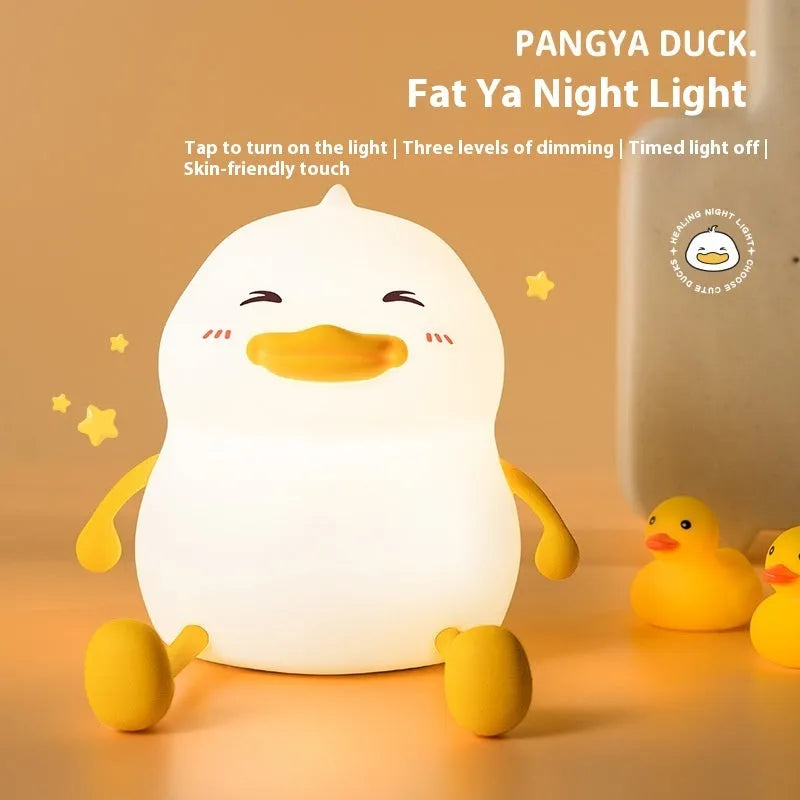 Chubby white rechargeable LED night light with silicone touch top on a wooden desk next to a phone.