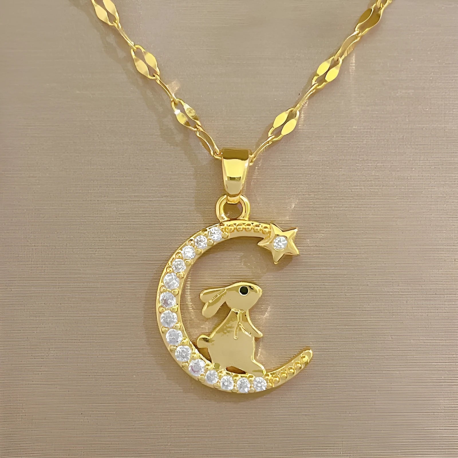 Gold colour copper rabbit and crescent moon full diamond necklace with micro inlay setting on studio background