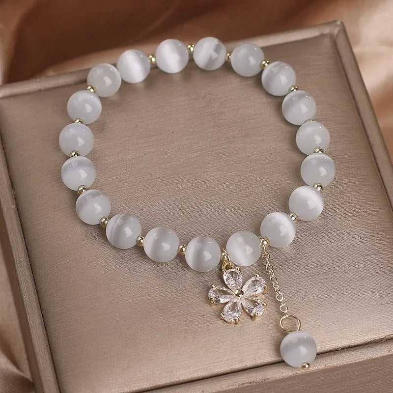 White cat's eye crystal bracelet with a silver flower tassel and safety buckle.