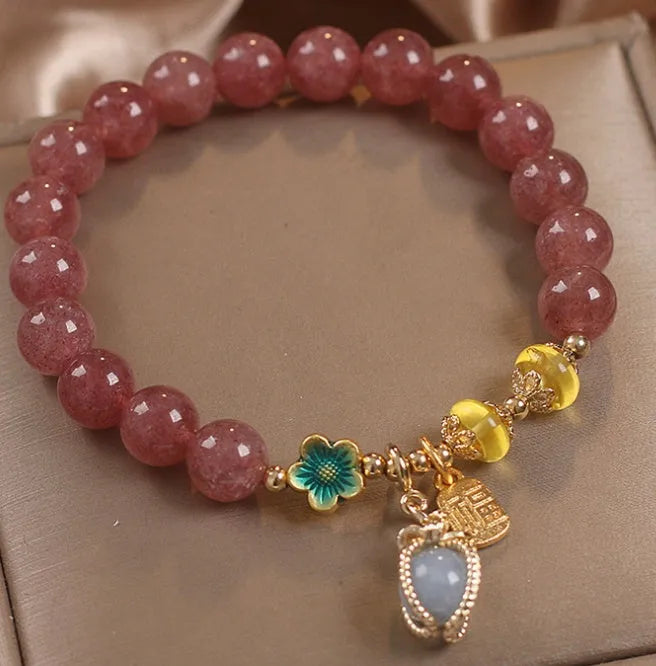 Red women's beaded bracelet made with natural strawberry quartz stones, alloy spacers, and rhinestone accents.