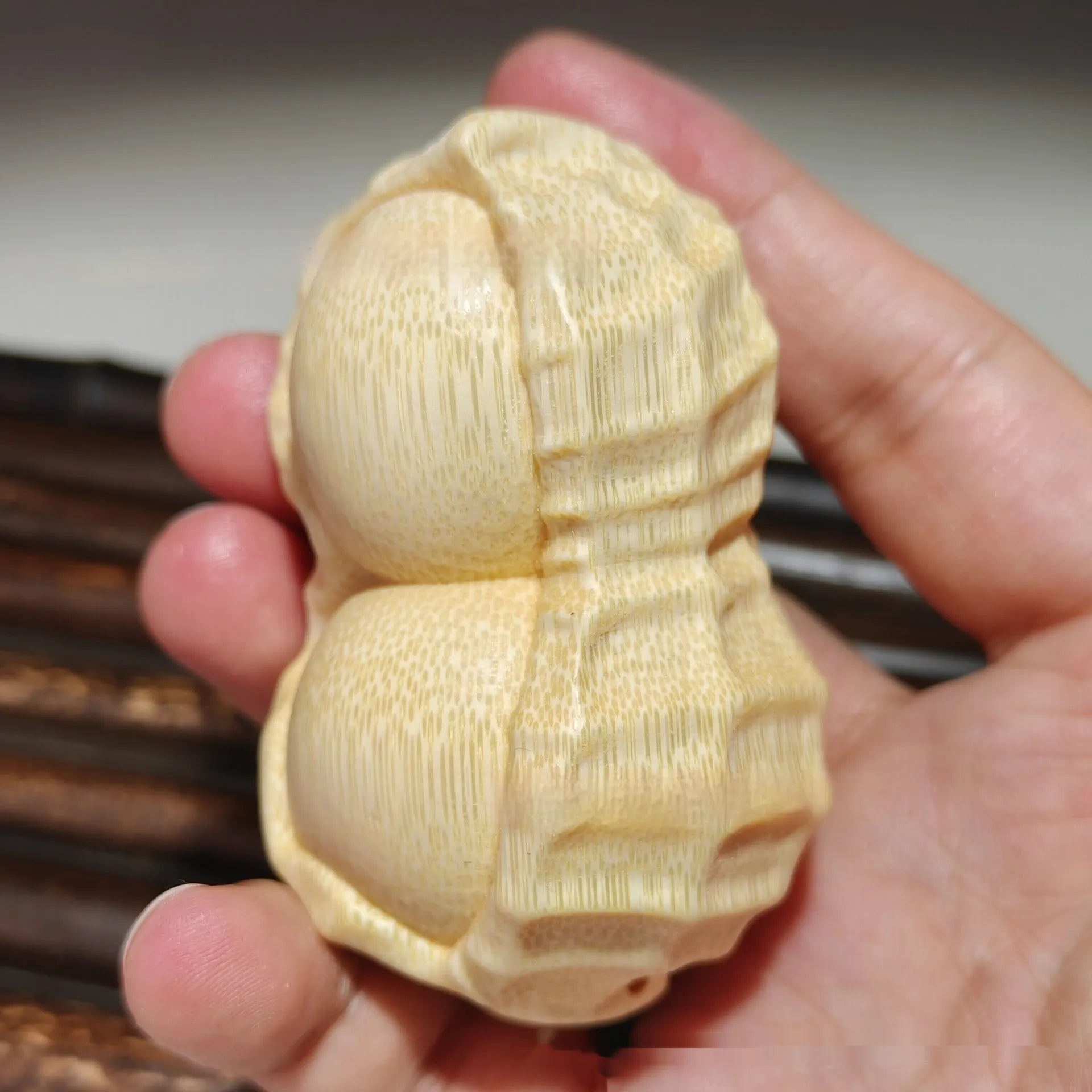 Solid natural bamboo carved peanut ornament with modern simple design on a wooden surface.