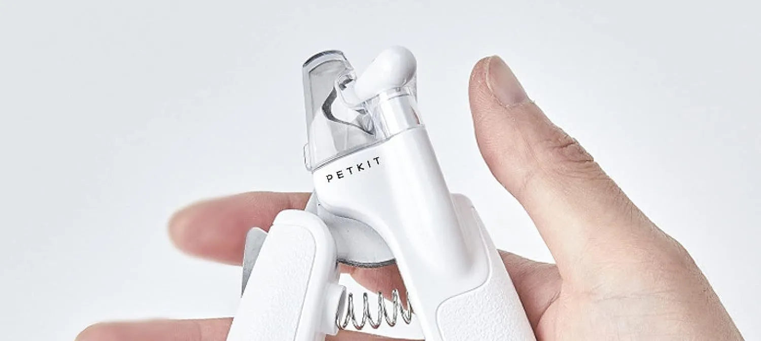 White pet nail clippers with LED light, anti-splash guard, and a nail file on a table.