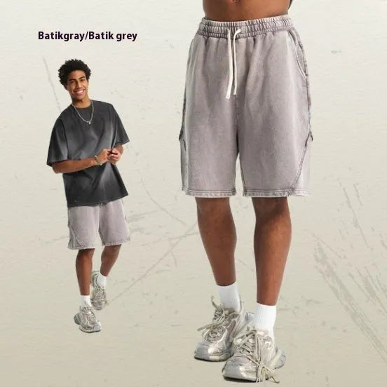 Man wearing loose fit batik washed cotton terry shorts with patch craft detailing in a street fashion style.