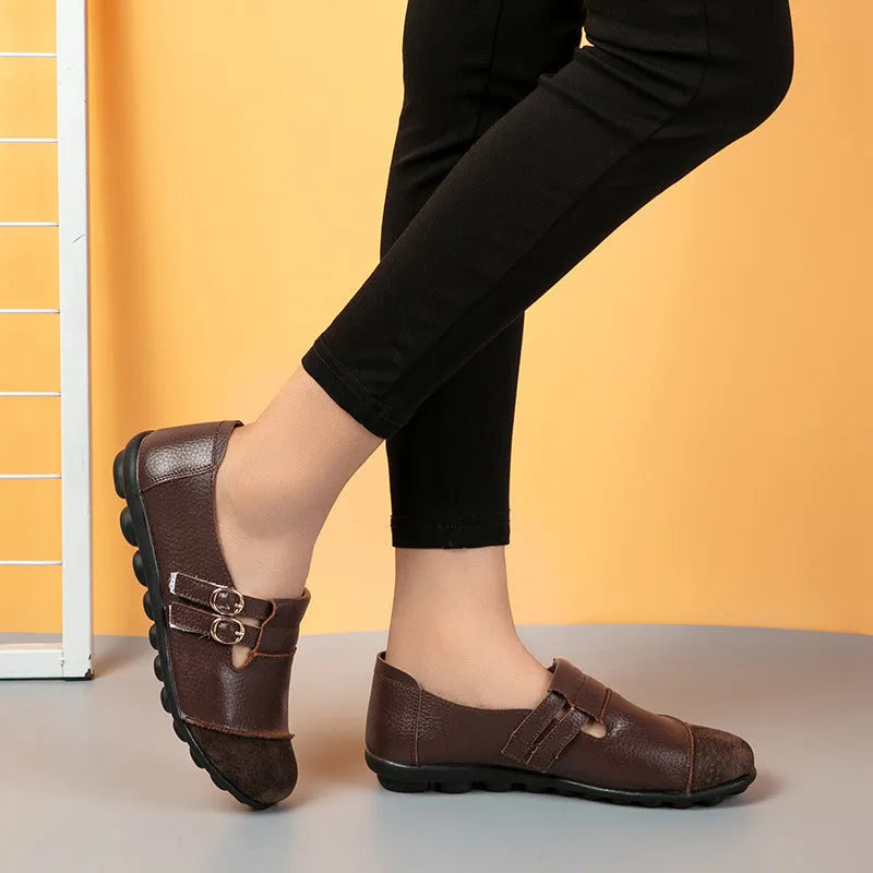 A pair of casual black flat shoes with a round toe, Velcro strap, and cow split leather upper.