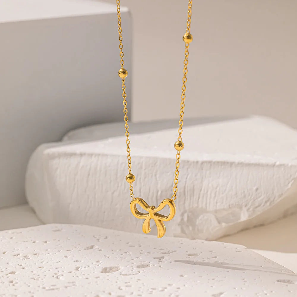 Gold electroplated bow necklace on cross chain with adjustable length