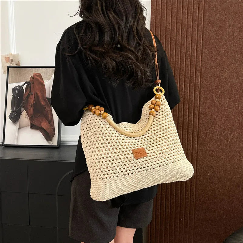 Knitted tote beach bag in bucket shape with crossbody strap showing contrast stitching details
