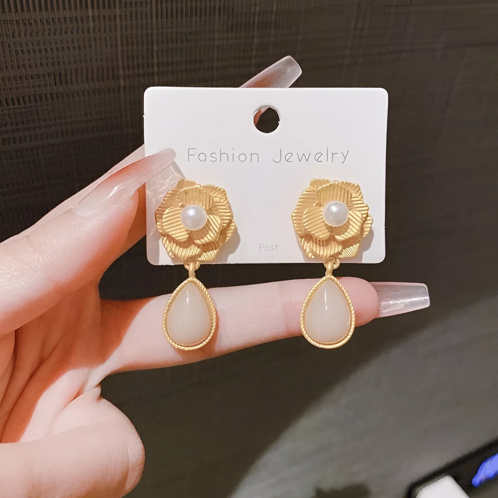 Gold flower stud earrings with a pearl, opal, and needle rose design on a white background.
