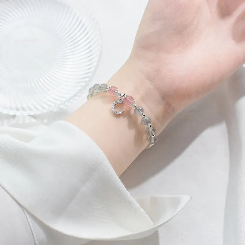 Natural moonstone bracelet with round beads, a crescent moon charm, and an adjustable silver chain on a wrist.