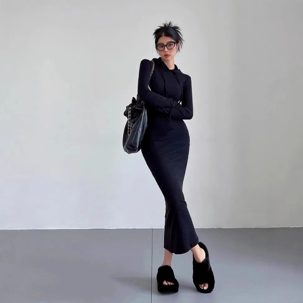 A woman wearing a grey high-waist hooded long sleeve sheath dress, knee-length pullover style.