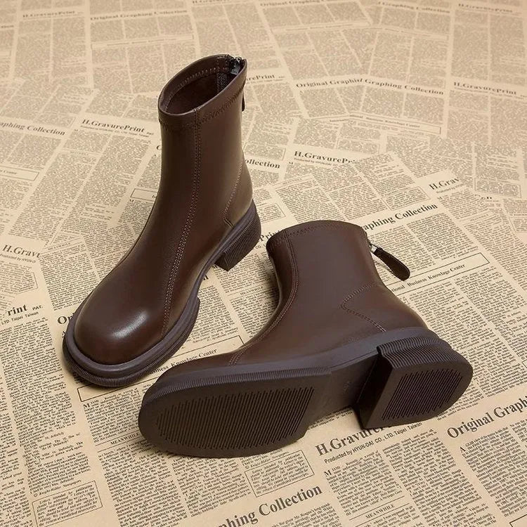 Women's black flat heel ankle boots with a back zipper and round toe, shown on a foot.