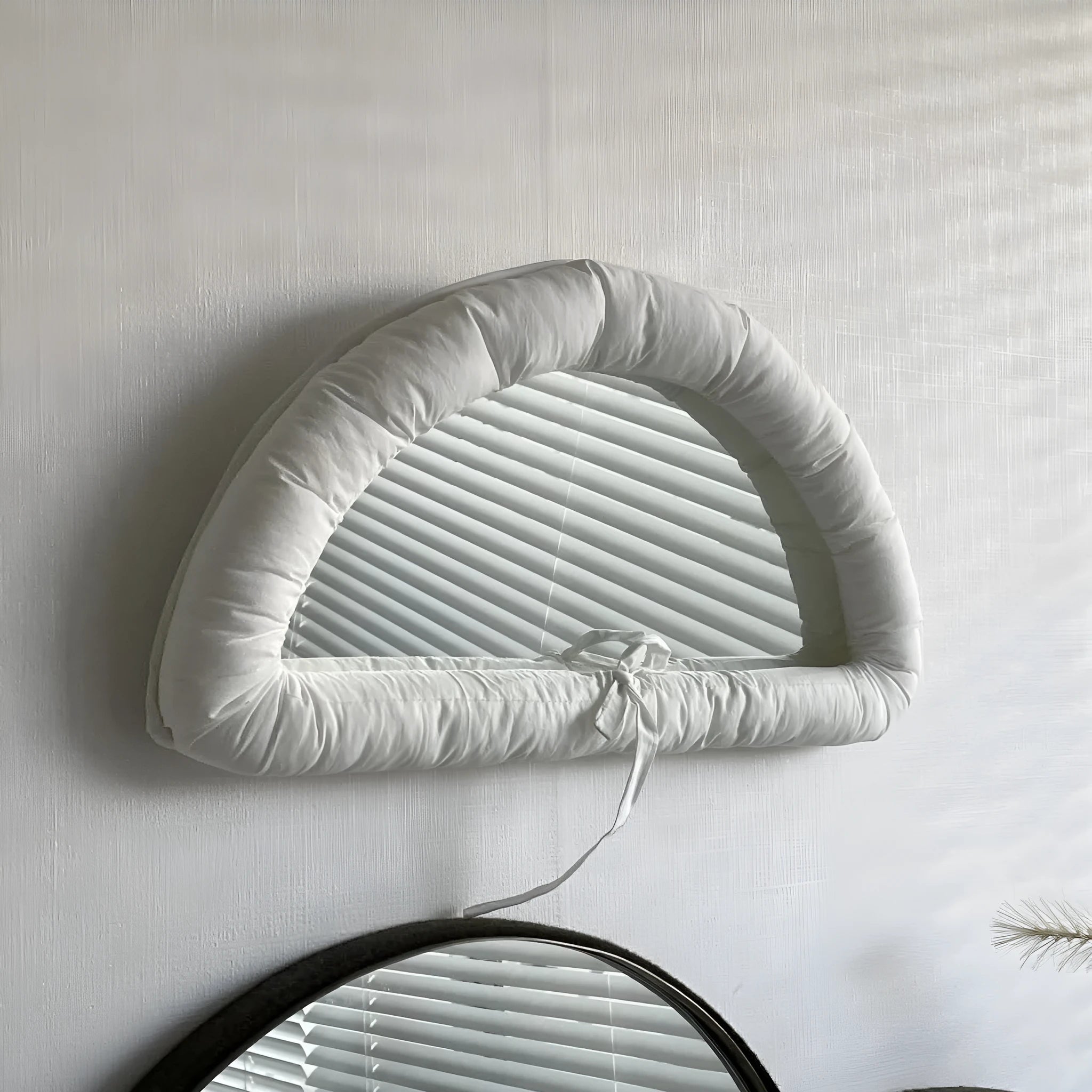 Rectangular white fabric mirror with soft filling hanging on a wall