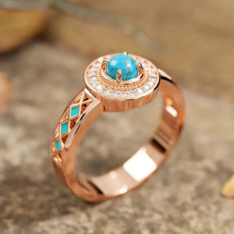 Women's rose gold coloured copper ring with geometric shape and inlaid turquoise zircon stones.
