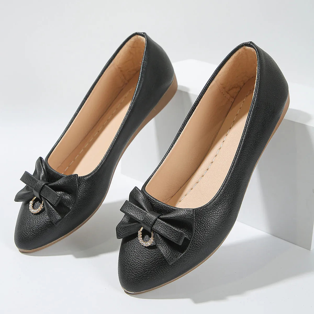 Women's beige flat casual slip-on shoes with a bowknot and shallow mouth design on a white background.