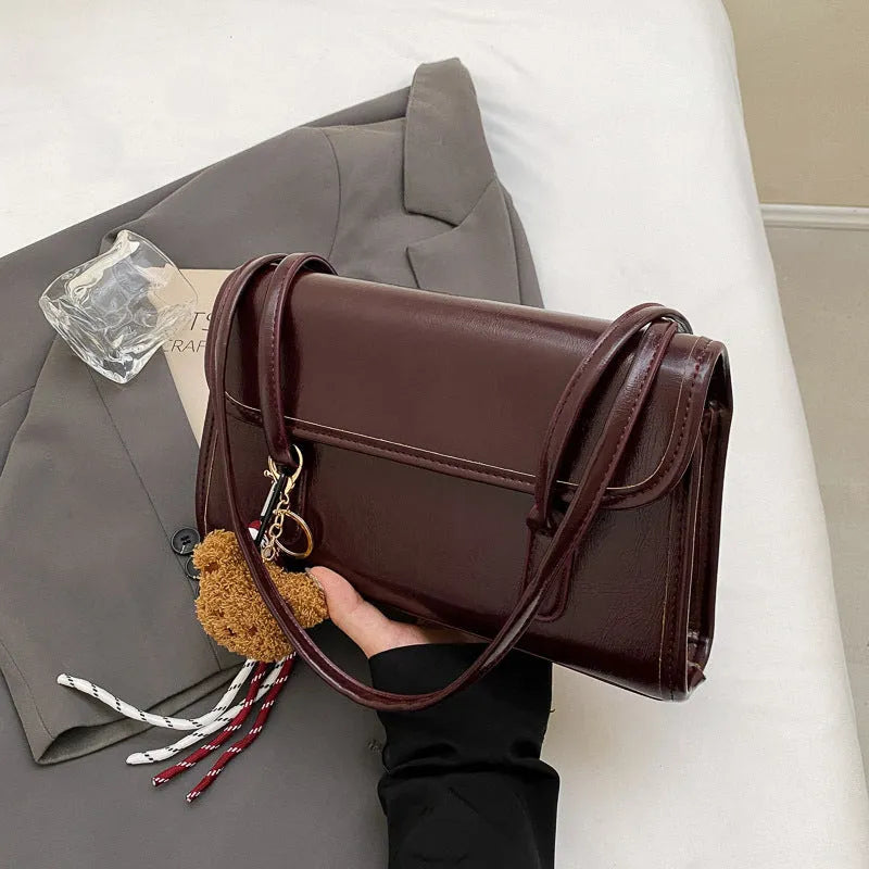 Brown women's PU leather shoulder bag with a square shape, double straps, and a detachable pendant.