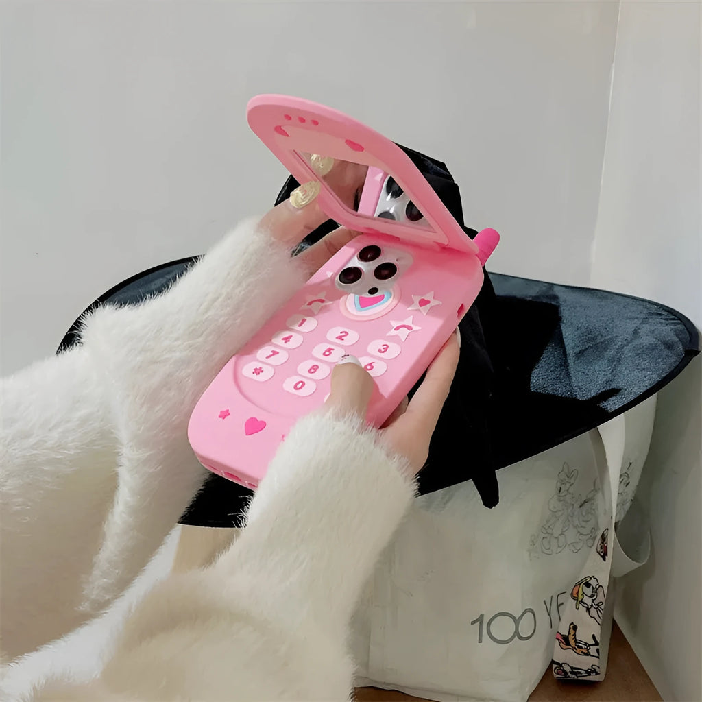 Pink silicone flip phone case open to show built-in mirror and iPhone compatibility.