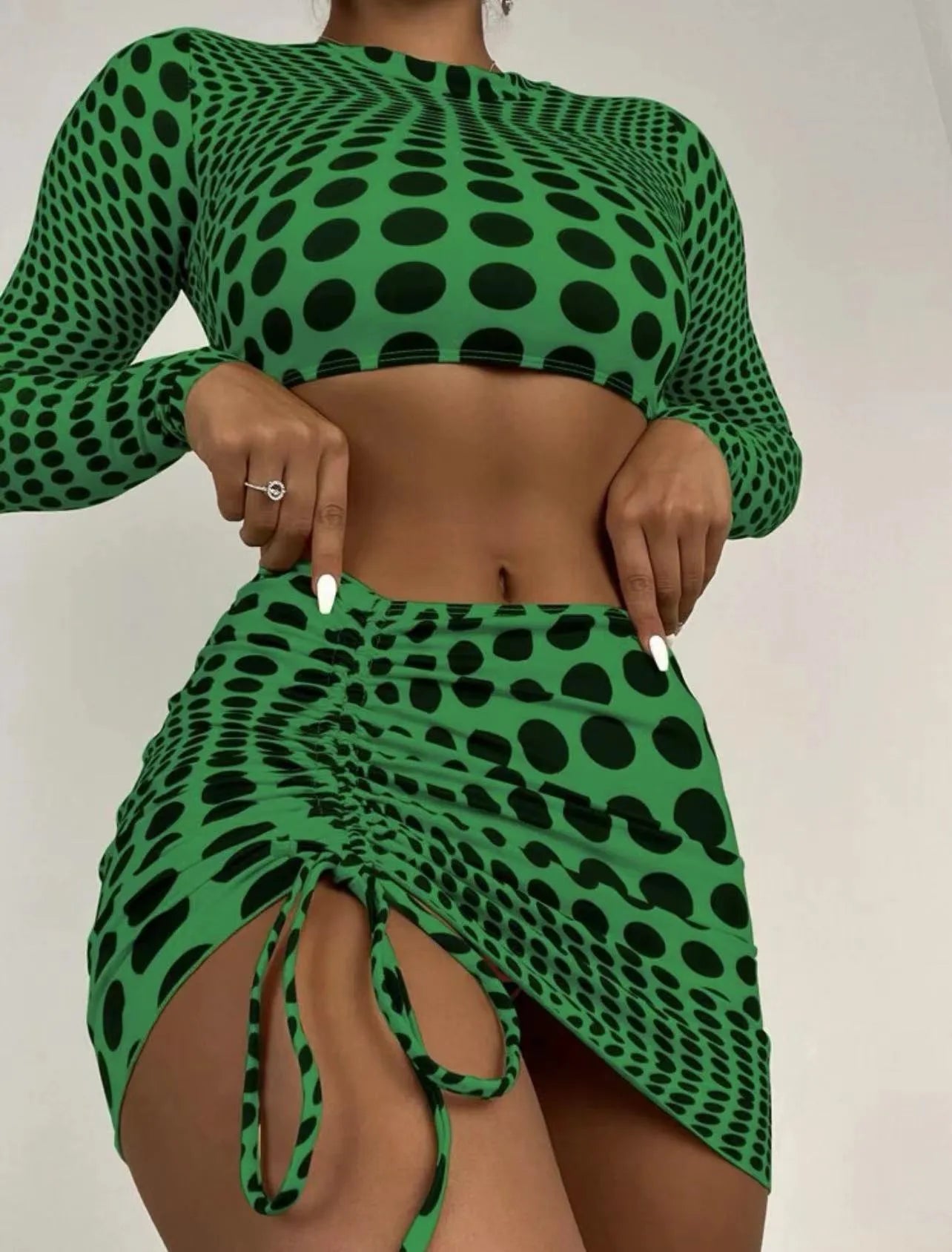 Women's green polka dot three-piece swimsuit set showing bra top and matching skirt