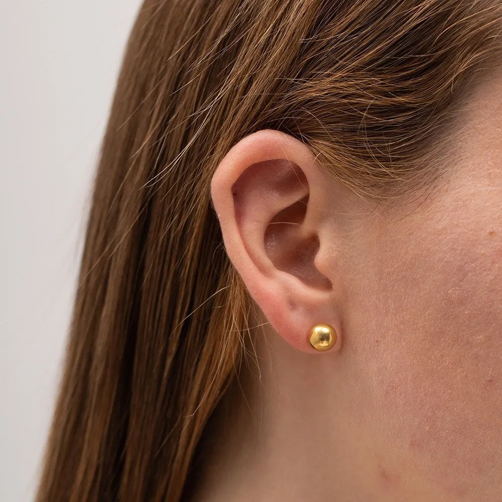 Stainless steel ball stud earrings in gold and silver finishes on a grey background.