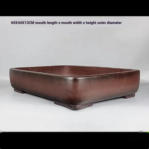 Handmade rectangular purple clay flower pot for indoor plants on a table.