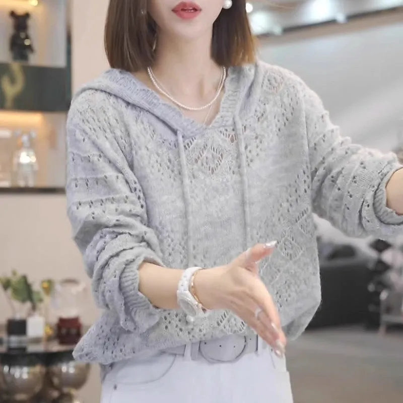 Women's white crochet knit hooded longsuit undershirt on a hanger, showing long sleeves and textured fabric.