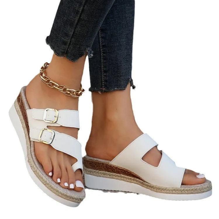 White patent leather wedge sandals with woven upper and peep toe design on a neutral background