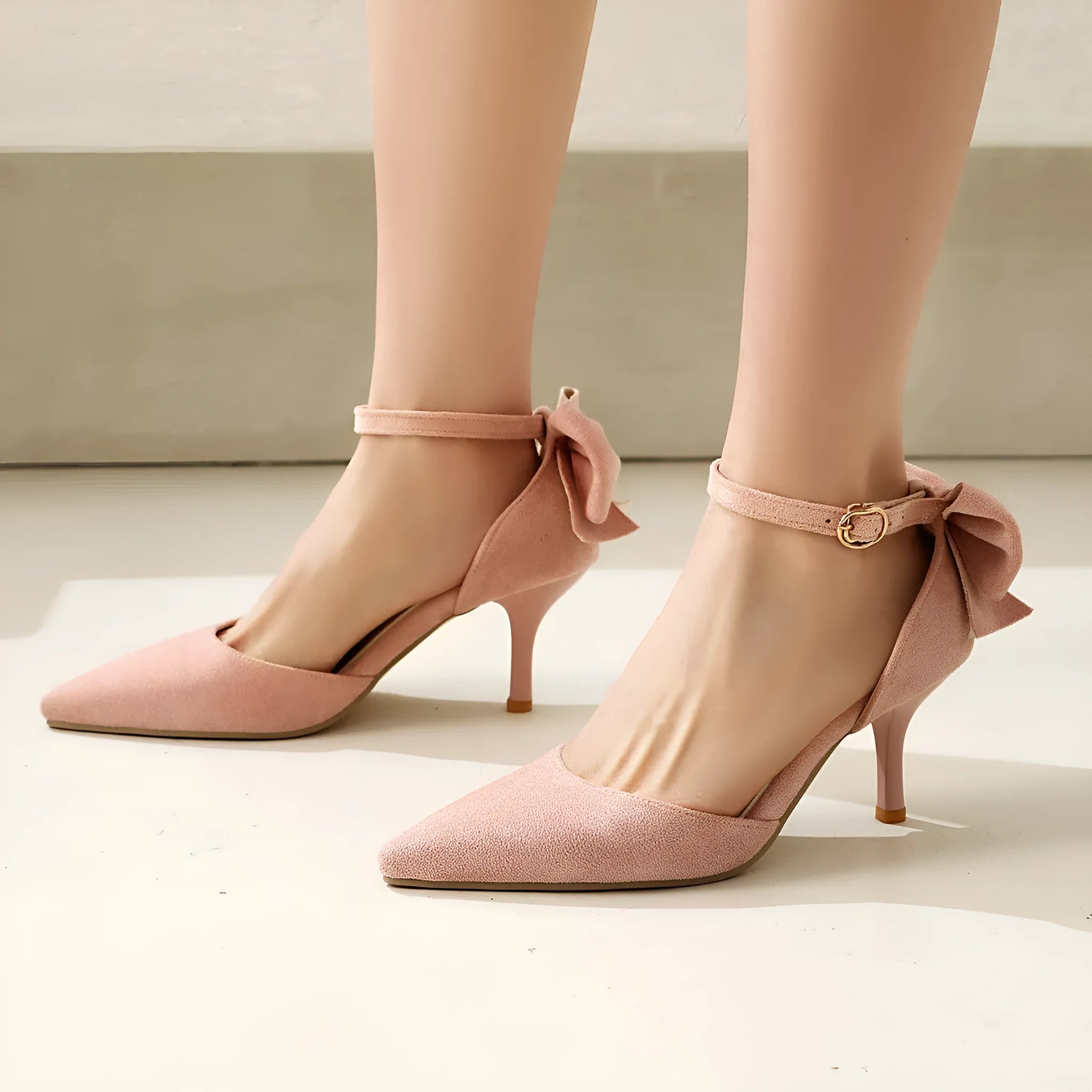 Black suede stiletto high heels with pointed toe, ankle buckle, and decorative bow knot.