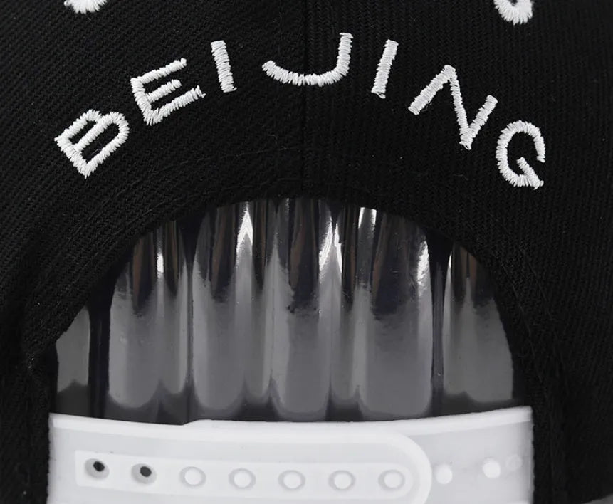 Cotton baseball cap with embroidered letters on the front, shown in black and white colours.