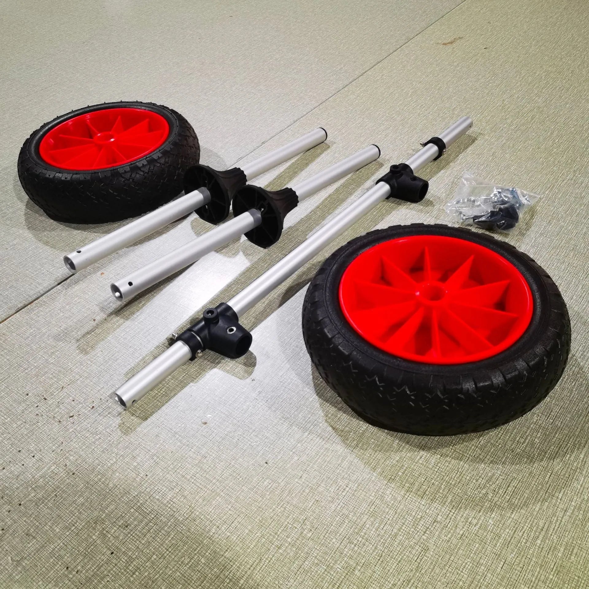 Foldable aluminium kayak cart with upright pole platform and wheels on a beach.