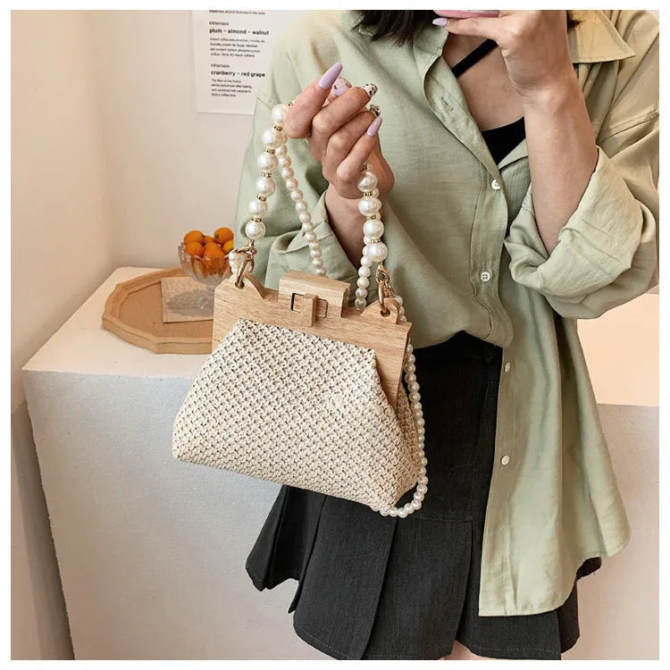Beige woven straw women's shoulder bag with pearl chain detail, showing interior zipper pockets.