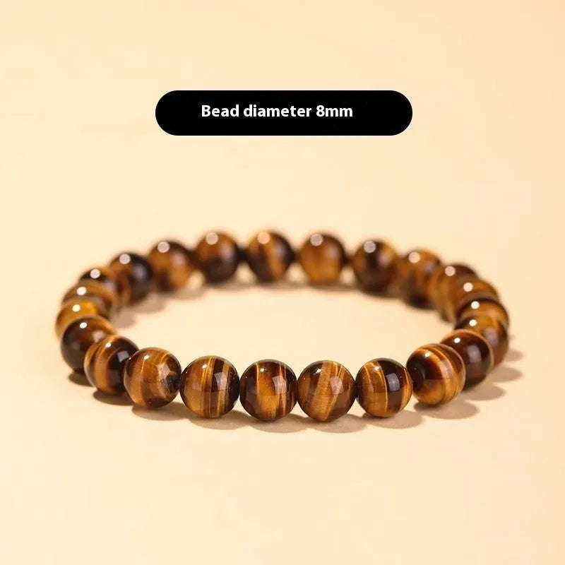 Single circle tigereye stone Buddhist prayer beads bracelet on wrist, showing ethnic design.