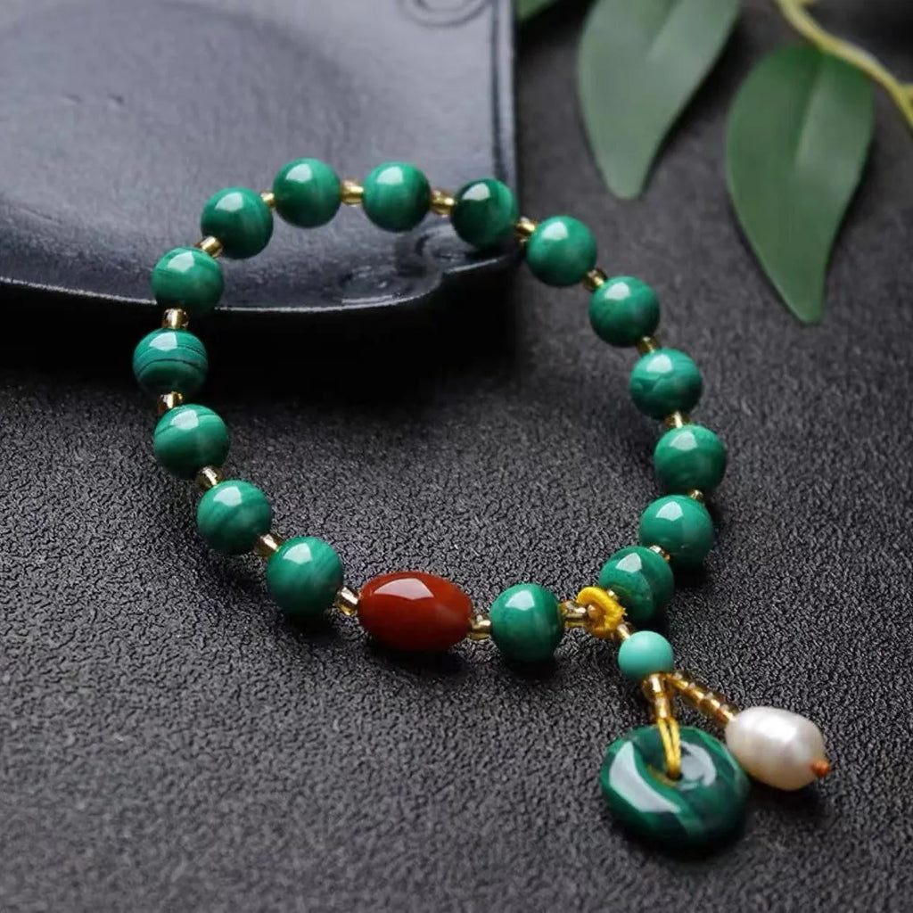 Natural malachite and red agate barrel bead bracelet with silver fittings on a woven elastic cord.