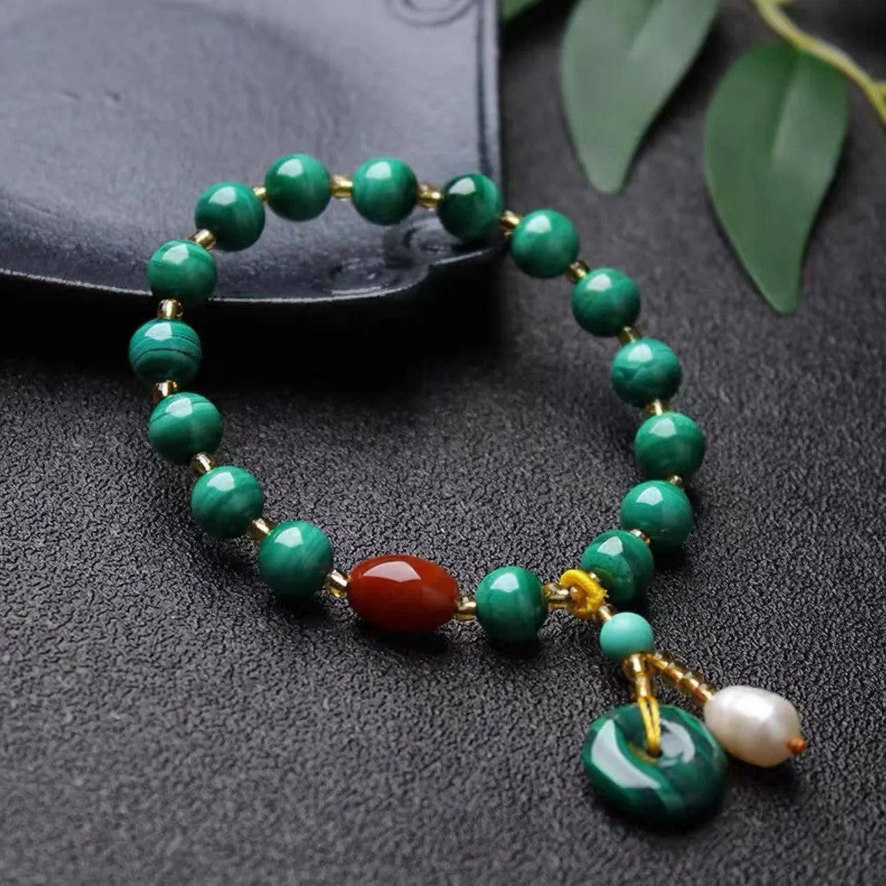 Natural malachite and red agate barrel bead bracelet with silver fittings on a woven elastic cord.