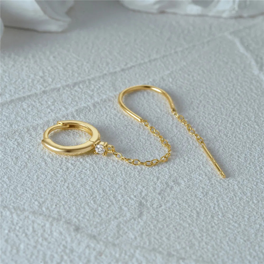 Close-up of a women's S925 sterling silver stud earring with a diamond flower, chain, and tassel design in a gold colour.