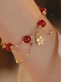 Red agate double layer women's bracelet with peach blossom design on adjustable string.