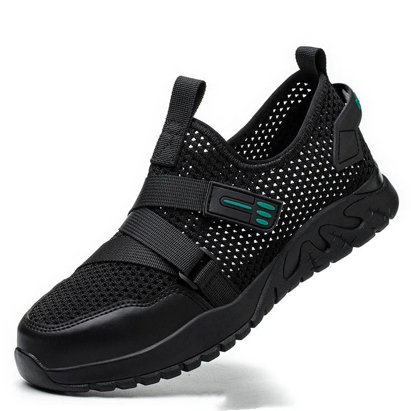 Men's grey safety work shoes with a woven upper and thick rubber sole on a work site background.