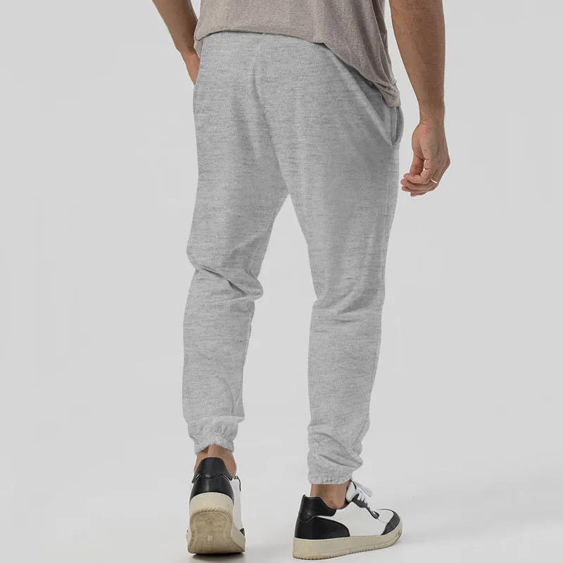 Men's grey track sweatpants with elastic waistband and straight-leg tapered fit