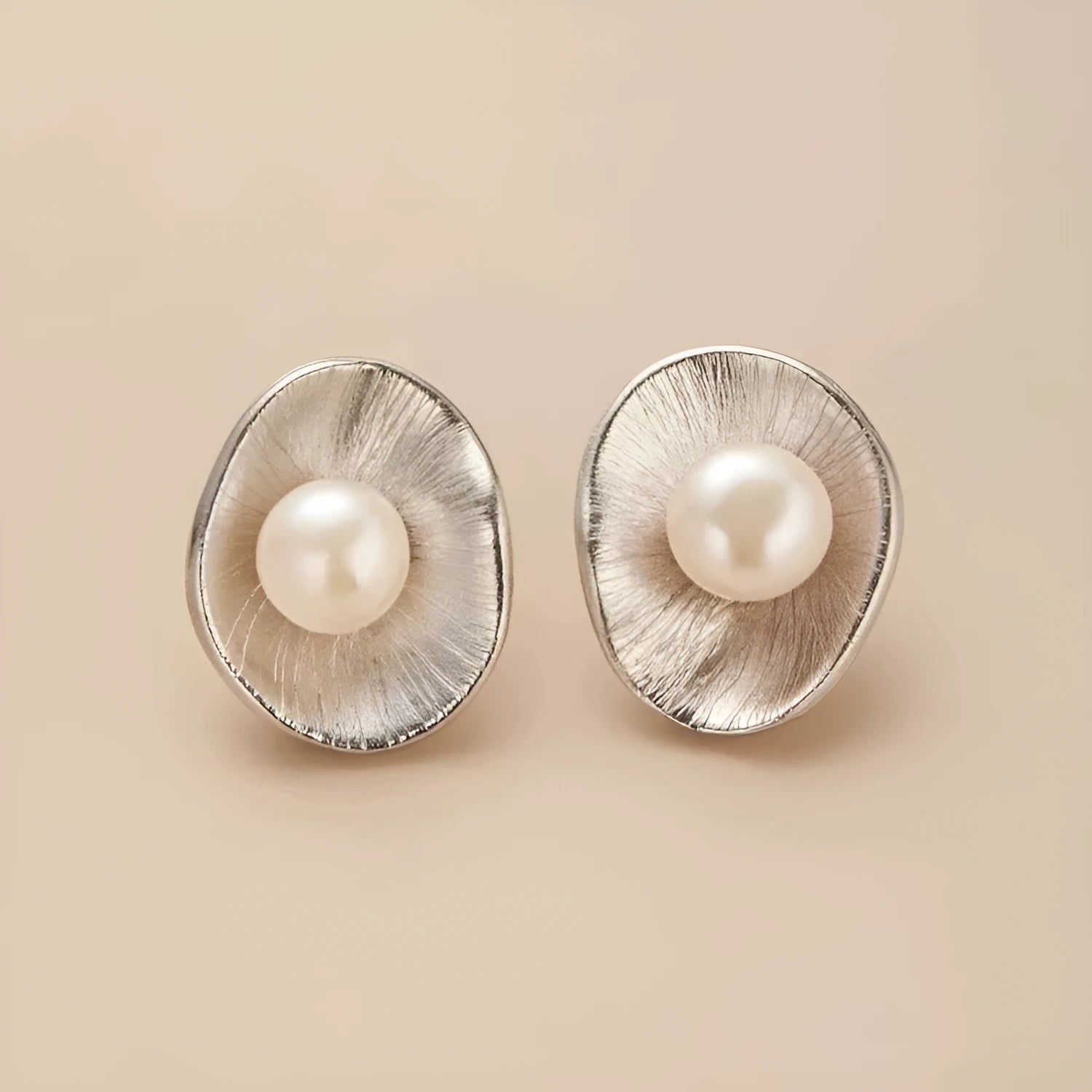 A pair of gold geometric sterling silver ear studs with small white pearl details on a post back.